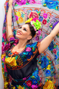 Mexican woman in traditional mexican dress hands up holding the skirt as background as peacock